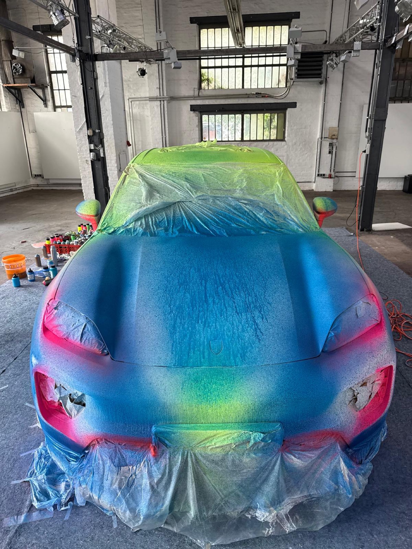 Der Macan während des Farbauftrags, Spraydosen im Vordergrund